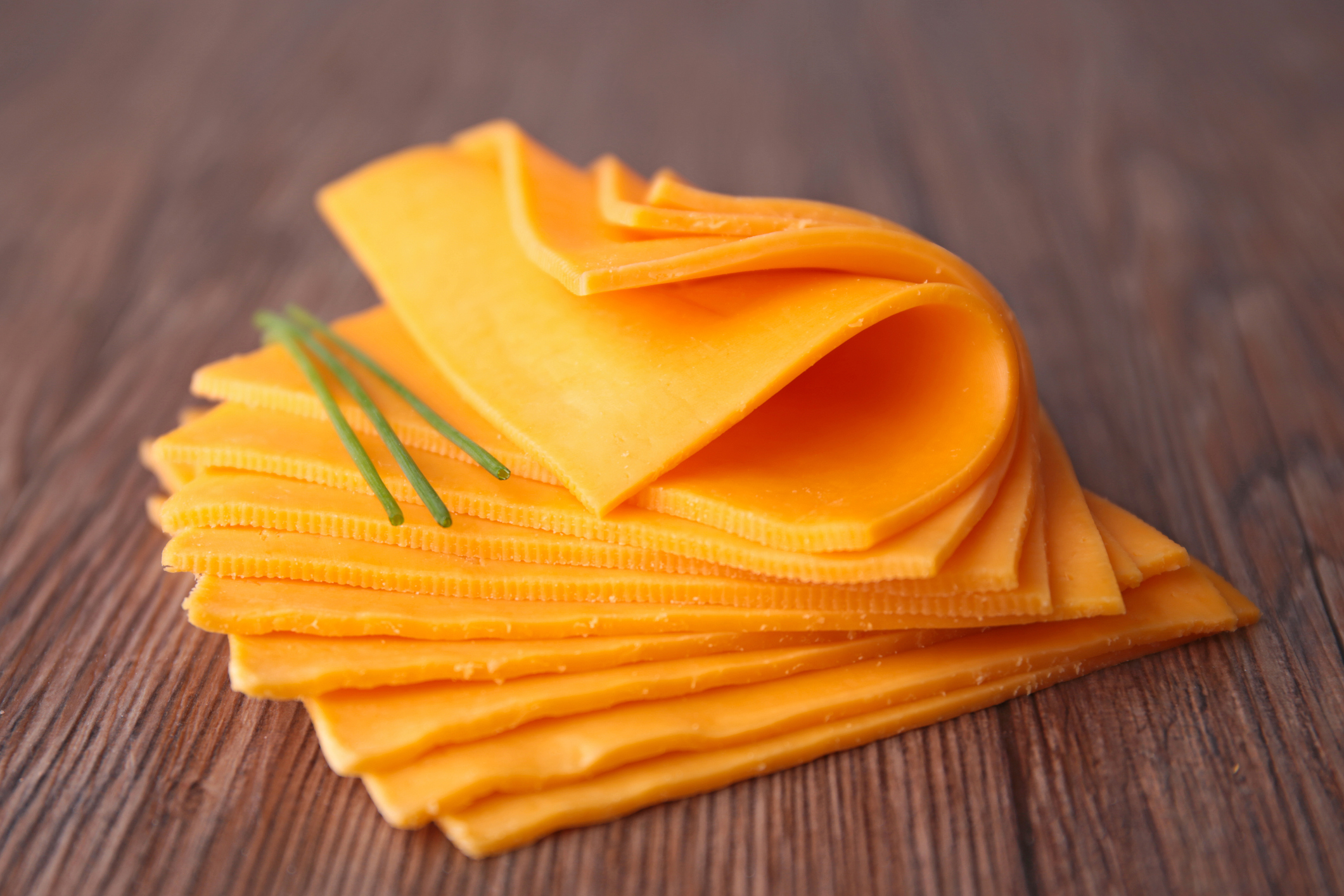 High Protein Processed Cheese stacked. Yellow with a sprig of chive.