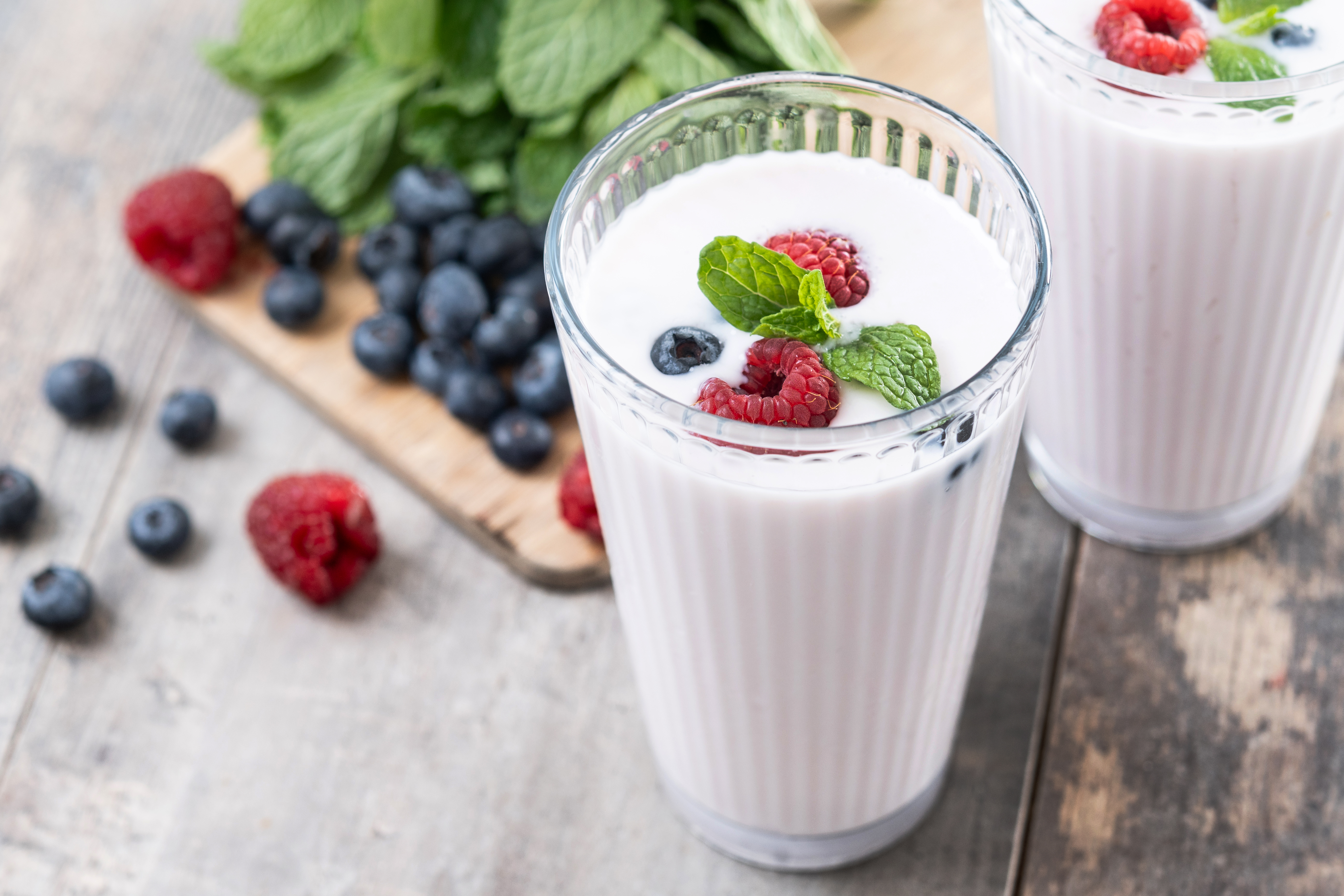 High Protein vanilla dairy drinks in tall glasses with blueberries, raspberries, and mint.