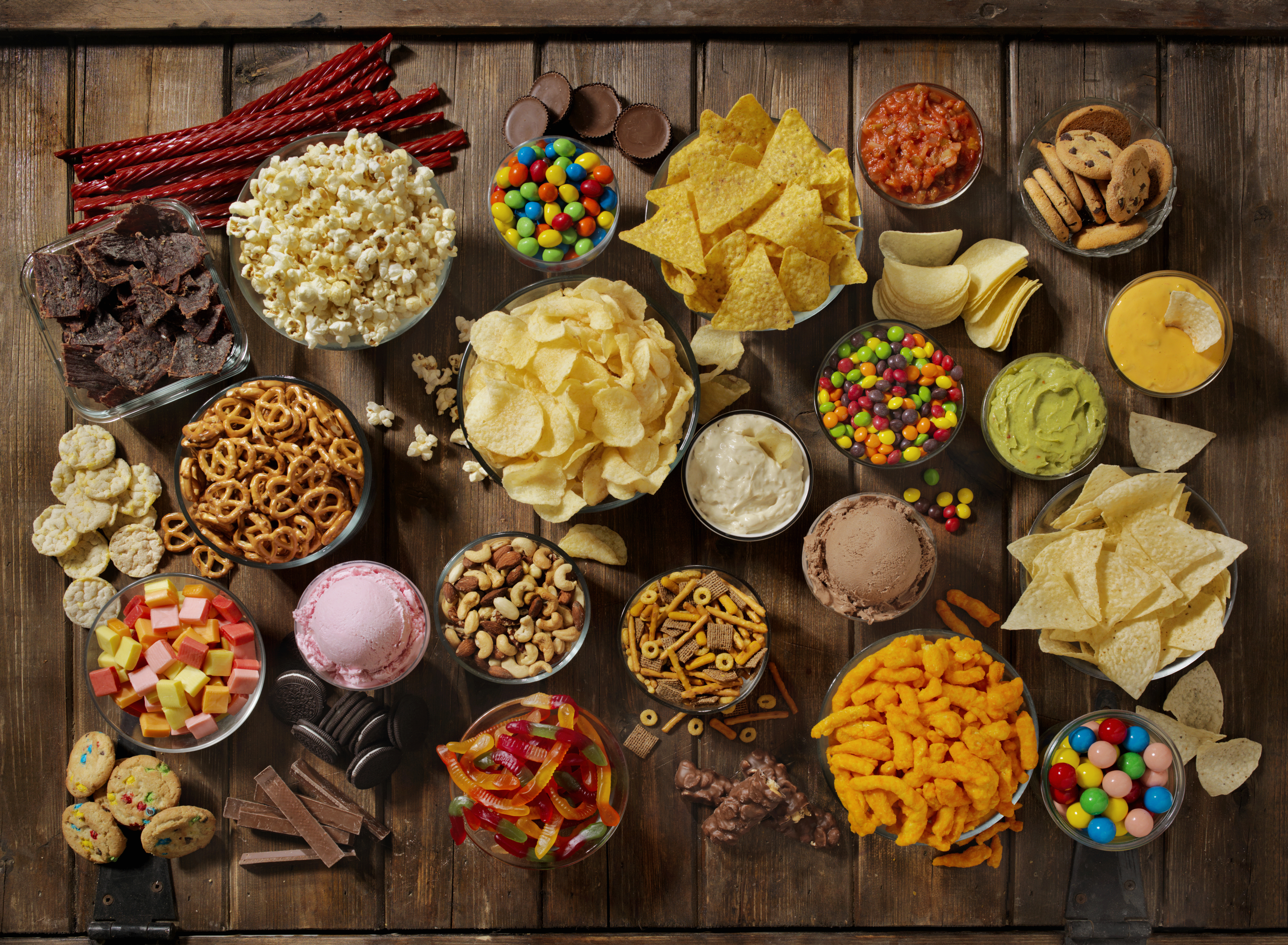 Array of protein snacks from pretzels, cheese puffs, candy, tortilla chips, and ice cream to guacamole and pretzels
