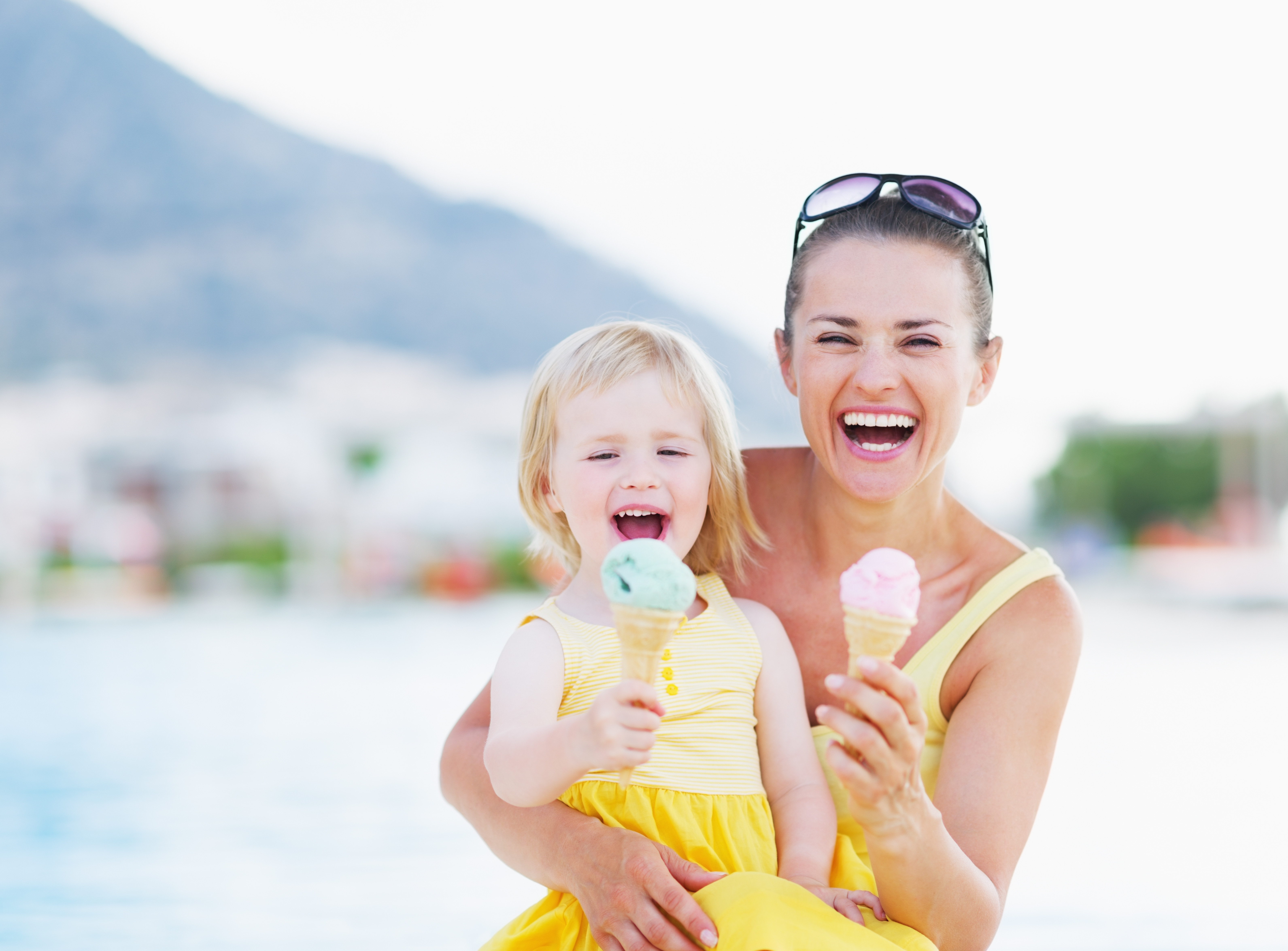 Mom and daughter eating high protein ice cream outside. Smiling and Laughing.
