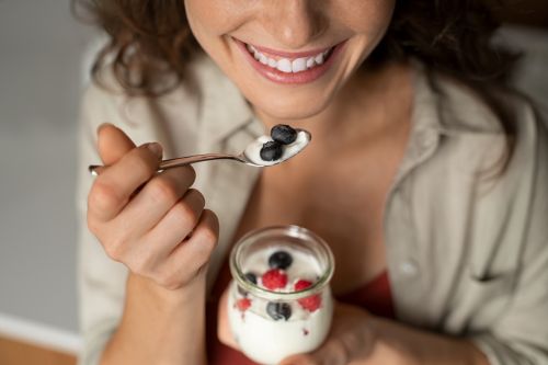 woman eating high protein vanilla yogurt with berries